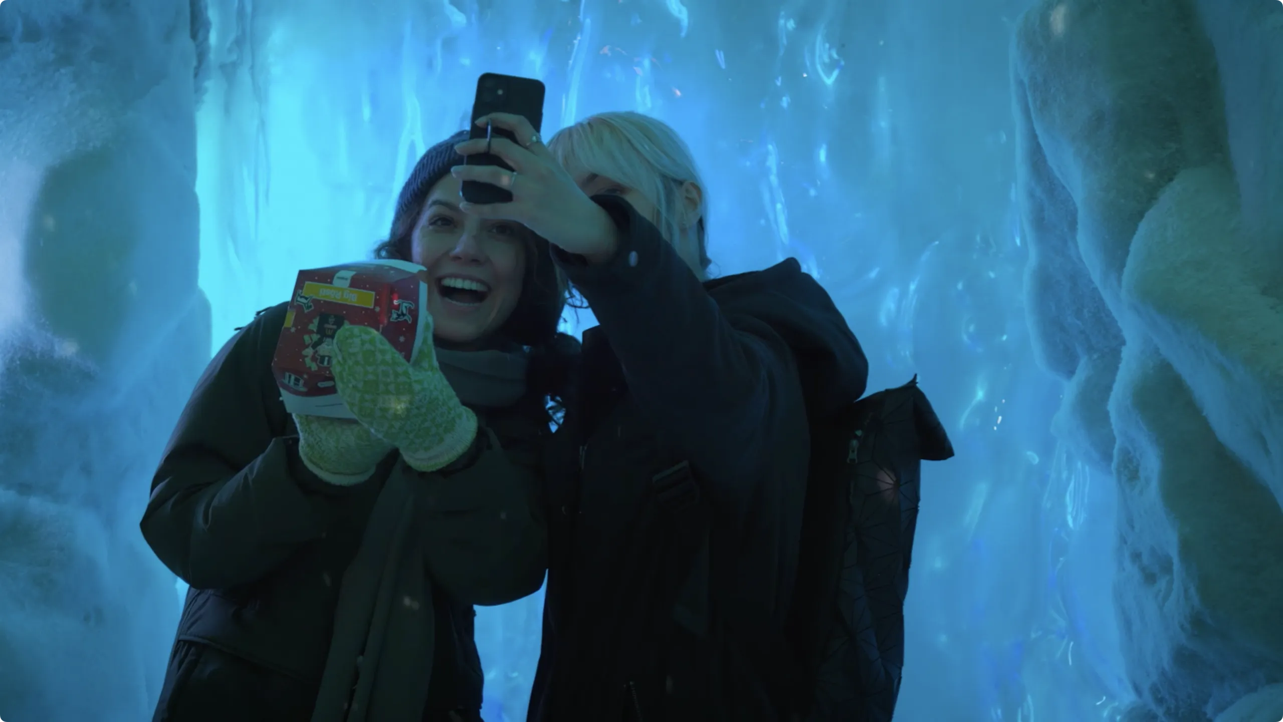 Two visitors take a selfie in the glowing blue ice world of the McDonald’s Wowball