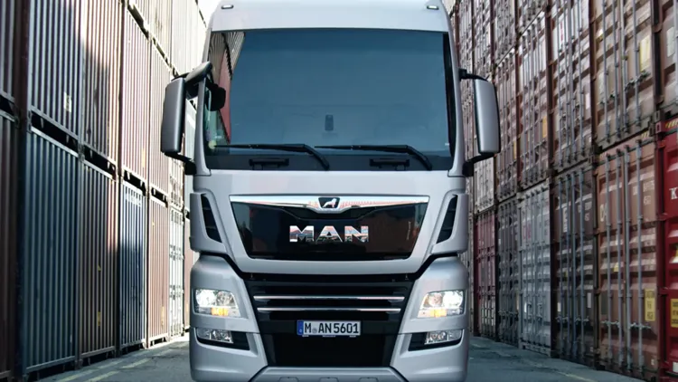Silver MAN truck heads straight through a lane of shipping containers in the MAN intro movie