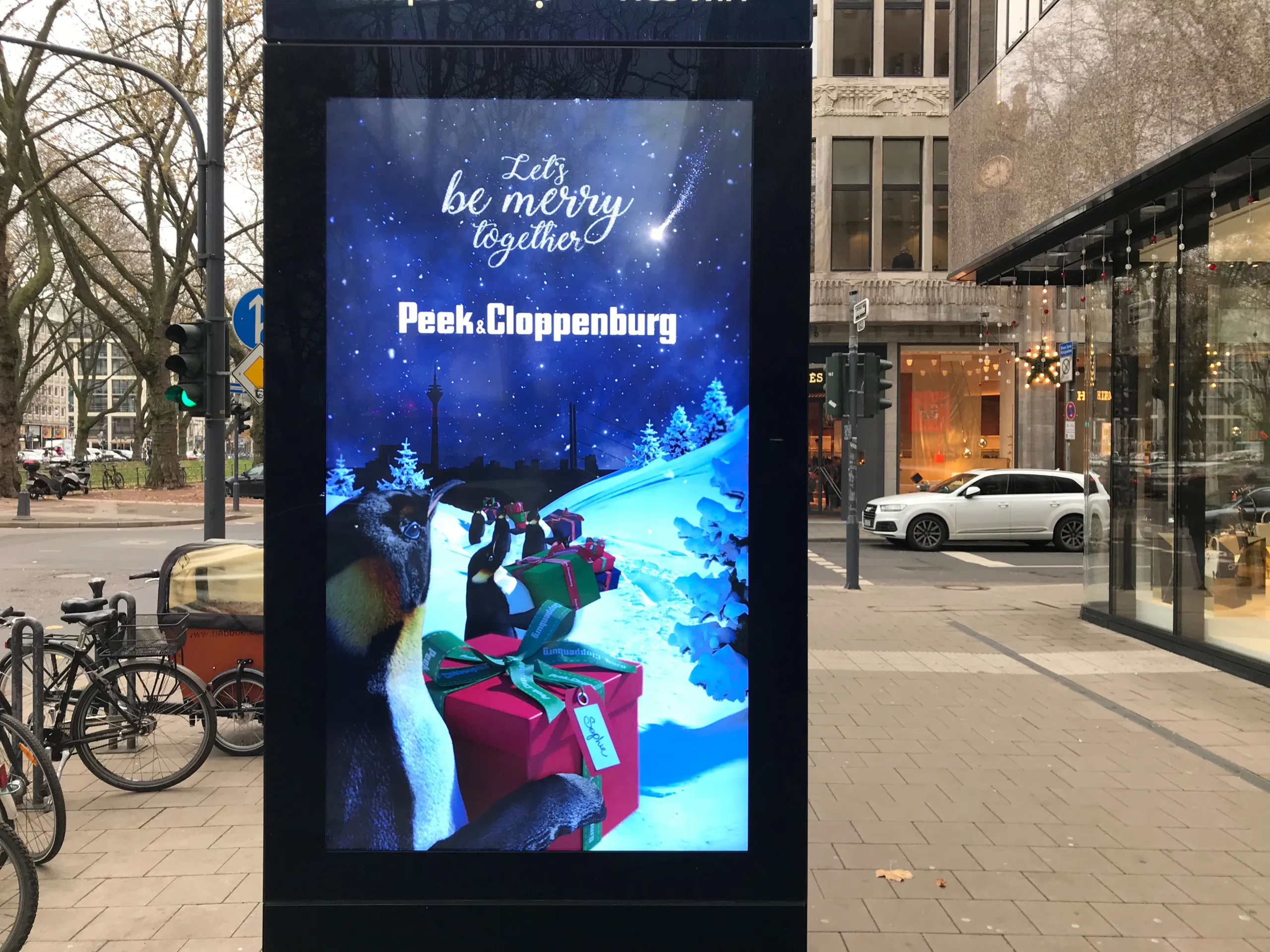 Digital street display showing Peek & Cloppenburg's penguin Christmas motif and "Let's be merry together"